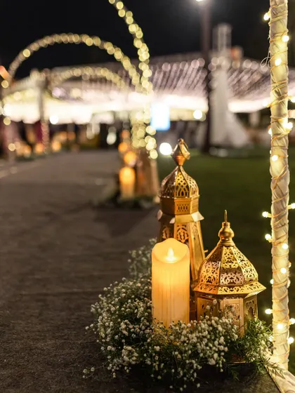 Golden lanterns and candles line an entryway, casting a warm and romantic glow for an evening event.