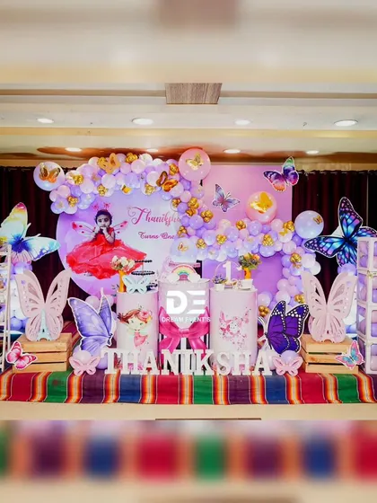 Another look at this colorful butterfly birthday party, showcasing the full stage with themed pedestals, 'BABY' blocks, and a large 'ONE' display shelf.