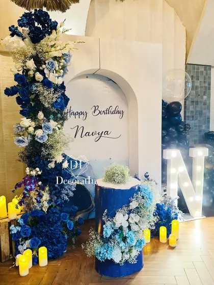 A cool and sophisticated setup for Navya's 15th birthday. The design uses a striking blue and white color palette, with a cascade of flowers, a custom-arched backdrop, and a large marquee 'N' for a personal touch.