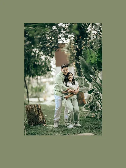 A framed portrait of a couple embracing in a garden, with a soft green border.