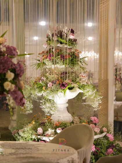 Another view of the magnificent floral fountain, showing how it anchors the space and creates a stunning focal point from every angle. The cascading threads of light add to the magical effect.