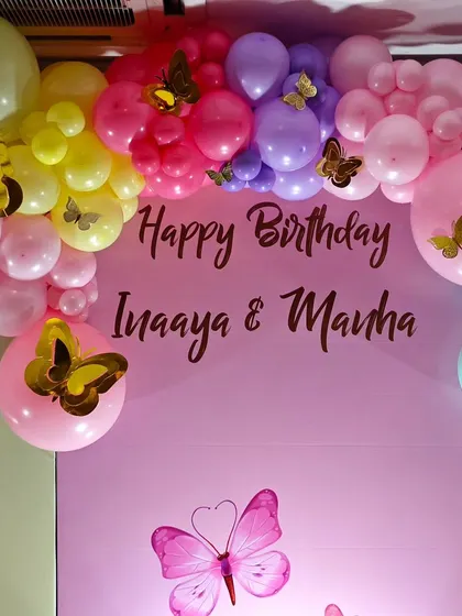 The personalized backdrop for the twin butterfly party, framed by a vibrant balloon arch.