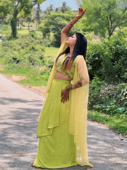 An artistic pose in the lime green fusion wear, showcasing the flowy cape and embroidered top.