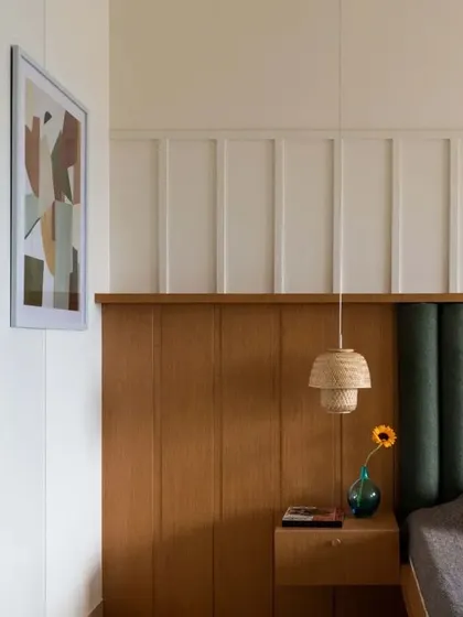 This close-up highlights the material combination in the master bedroom, with wood, fabric, and painted paneling creating a layered, tactile experience.