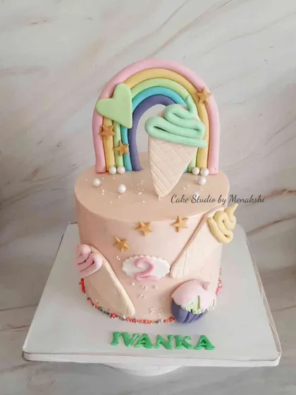 A pretty ice cream themed cake for Ivanka's second birthday. The design features a rainbow and lots of colorful, edible ice cream cones and cupcakes.