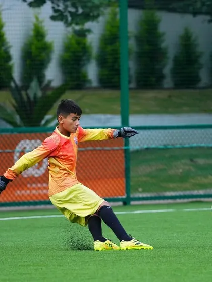 A U13 goalkeeper practices his distribution with a powerful kick during a training session.
