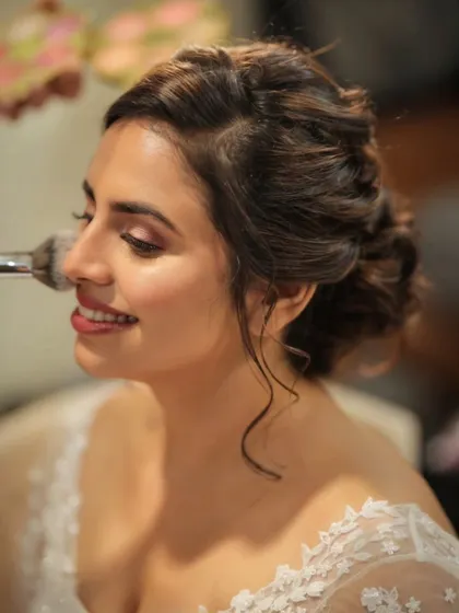 A happy bride is the most beautiful bride. Here's a candid moment of putting the finishing touches on her textured updo, complete with soft tendrils to frame her smiling face.