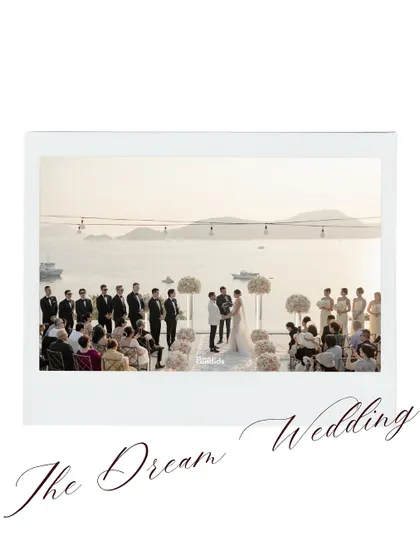 A wide shot of the stunning white wedding setup, overlooking the ocean. It captures the scale and beauty of their dream wedding.