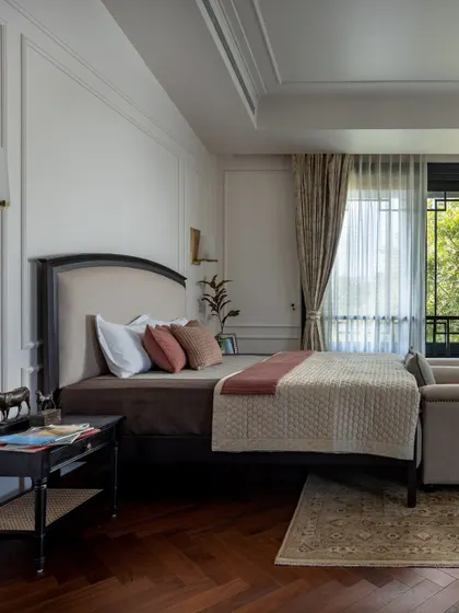 This bedroom in the House of Verandahs is a private retreat that remains connected to the home's overall design language. Parquet floors and classic wall mouldings speak to colonial proportions, while the view opens directly onto the lush outdoors.