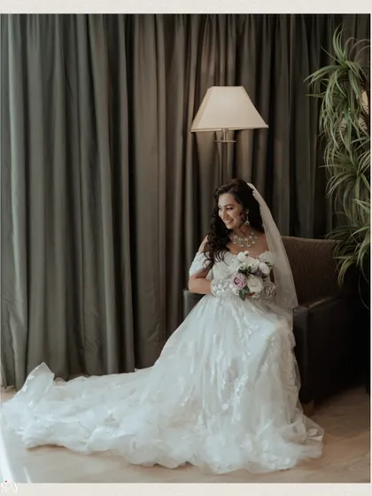 The bride seated gracefully, her beautiful white wedding gown and veil cascading around her.