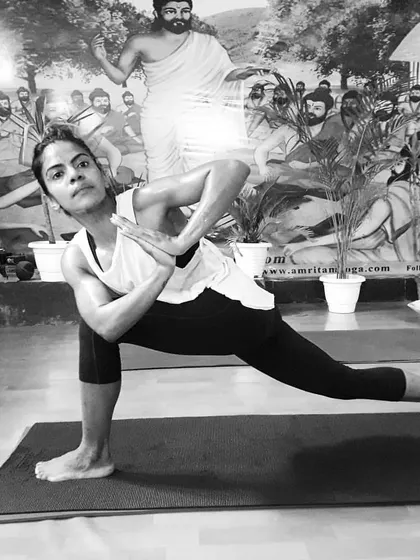A black and white shot of a student in a powerful lunge with a prayer twist. This pose builds heat, strength, and focus.