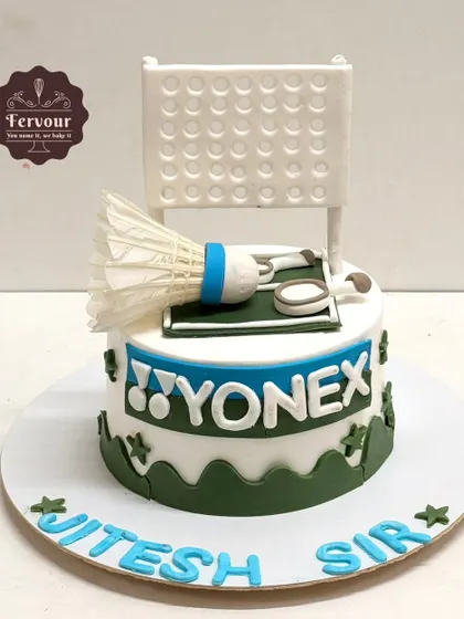 A badminton-themed cake designed for a coach. It features the Yonex logo, a net, and a shuttlecock, making it a highly personalized and thoughtful gift.
