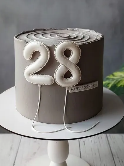 A classy and modern cake for a 28th birthday. The cool grey color and the white balloon numbers create a sophisticated and understated look.
