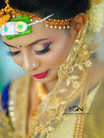 A close up of the intricate details of a muhurtham look. The shimmery gold eyeshadow and perfectly applied eyeliner make the eyes pop, while the traditional bindi and headpiece complete the look.