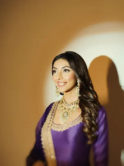 The soft, warm lighting in this photo enhances the golden embroidery of the outfit and the radiance of the makeup.