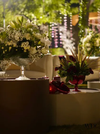 A beautiful contrast of colors and textures. A centerpiece of white lilies sits beside a smaller arrangement of red roses, creating a balanced and elegant tabletop look.
