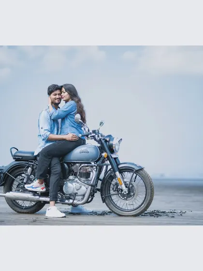 A cool and casual pre-wedding photo of a couple on a Royal Enfield motorcycle at Kelva Beach. This captures a fun, adventurous vibe for couples who want their photos to feel relaxed and authentic.