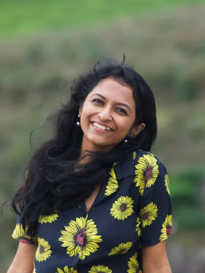 A bright, smiling portrait against the green hills of Munnar. This is a classic lifestyle shot that radiates positivity and natural charm.