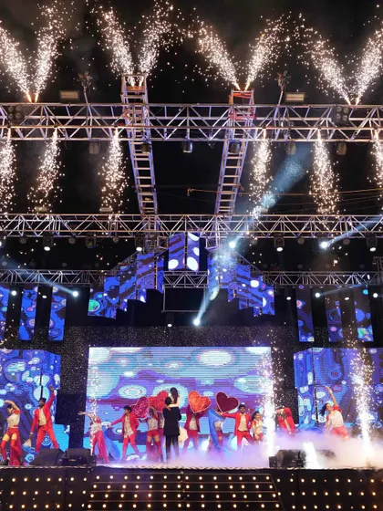 The entire stage comes alive with pyrotechnics during a dance performance, highlighting the dynamic and high-energy production value of the Sangeet.