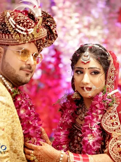 A candid shot of the couple during their Jaimala ceremony, captured against a vibrant floral backdrop.