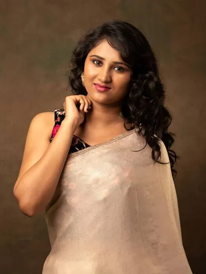 A warm and friendly portrait of the actress in her saree, showcasing a beautiful, natural smile.