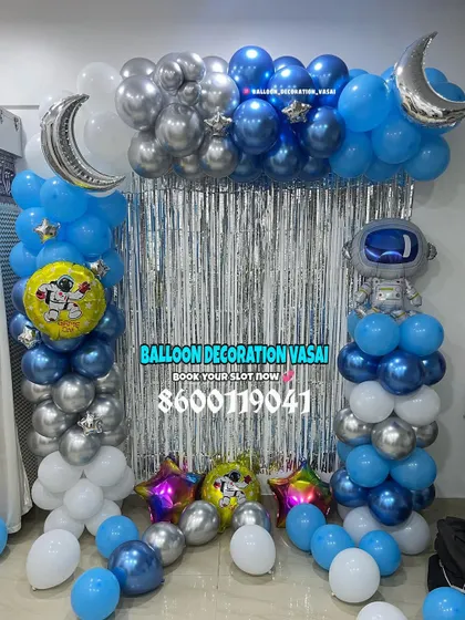 An outer space theme for an adventurous birthday. This setup includes a silver shimmer curtain, blue and silver balloons, and astronaut and moon foil balloons.