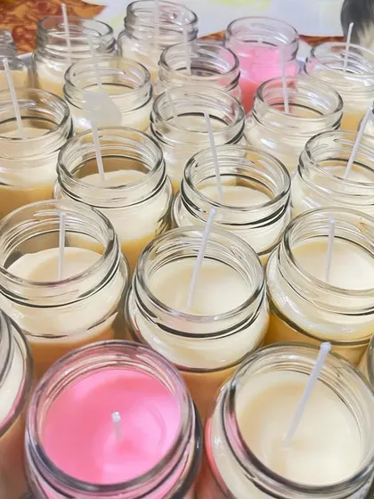 Pouring and setting a large batch of soy wax candles in glass jars. This is part of the process for fulfilling bulk orders for return gifts and party favors.