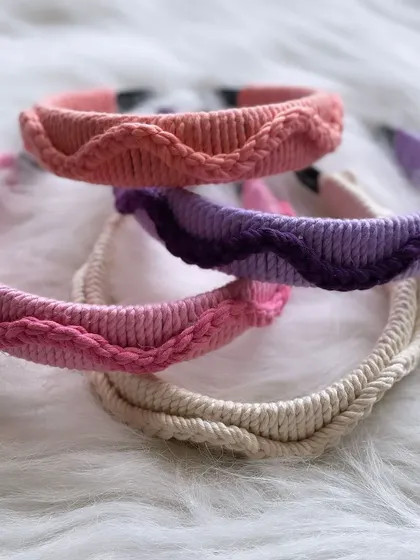 A different view of my stacked macrame hairbands, featuring four distinct designs and colors. From a simple twisted cord in off-white to a wavy pattern in purple, each one offers a unique boho touch.