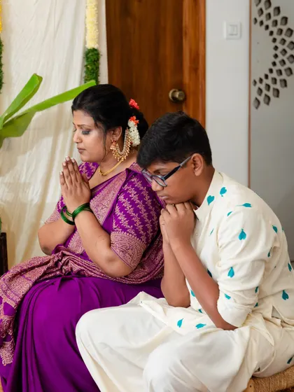 A moment of prayer during our housewarming. I designed my son's white kurta with blue heart embroidery and my own purple blouse to complement my saree, creating a coordinated and meaningful look for our family's special occasion.