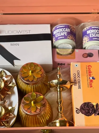 A premium gift box filled with festive items like Moroccan Escape candles, cookies, and traditional Indian decor.