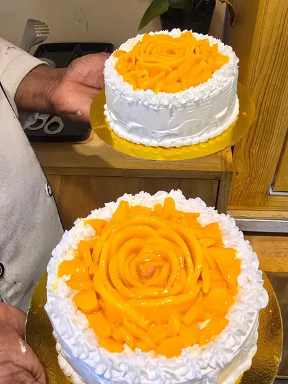 Real mango slices form roses on our seasonal mango cakes, with white cream piped around the fruit.