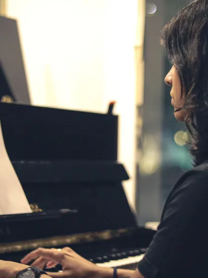 A pianist deeply focused during a performance. The quality of our instruments, like this Yamaha upright, helps musicians deliver their best sound.