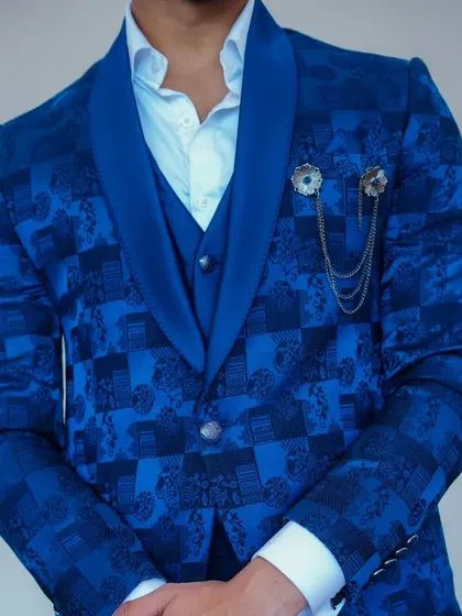 A close-up of the royal blue patterned suit, showing the texture of the fabric and the stylish chain accessory.