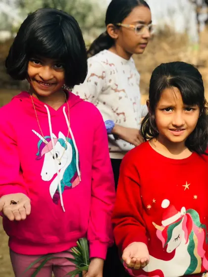 Two girls proudly hold up the earthworms they found during our composting showcase. They are learning that there's nothing to be scared of in nature.