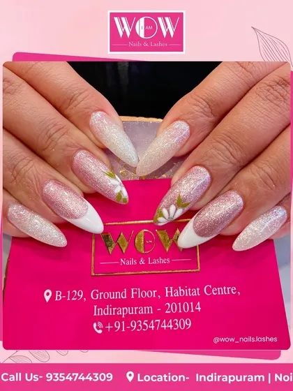 These long, stiletto extensions are a work of art, featuring a glittery pink and white ombré base with delicate white floral details. A beautiful and feminine choice.