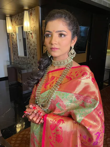 A stunning engagement look. The bride wears a beautiful pastel Kanchipuram saree with heavy jewelry and a soft, braided hairstyle.