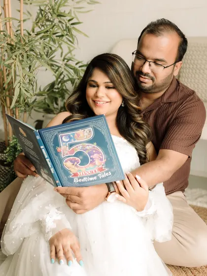 A cozy indoor maternity shot, with the couple reading a book of bedtime tales together.