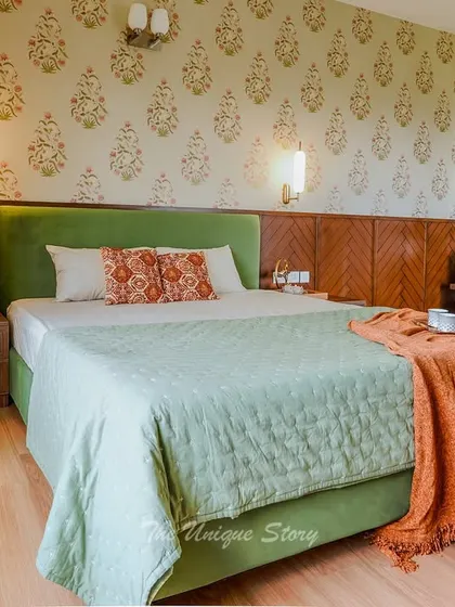 A master bedroom renovation that blends old and new. We designed a new green velvet upholstered bed and paired it with a traditional Indian block-print style wallpaper. The custom wooden headboard and nightstands add warmth and a touch of heritage.