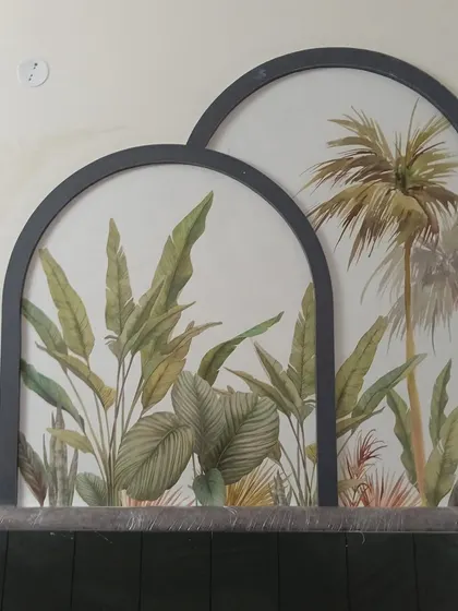 Tropical leaf murals framed as two separate arched panels. This is a stylish and contemporary way to incorporate wallpaper as wall art, creating a balanced and elegant feature.