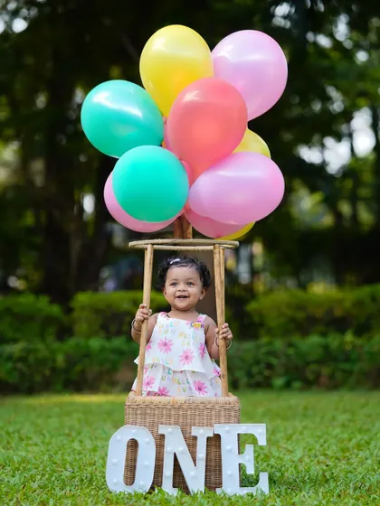 A happy smile from inside the hot-air balloon basket. This classic prop always brings out the joy in children during their first birthday photoshoots.