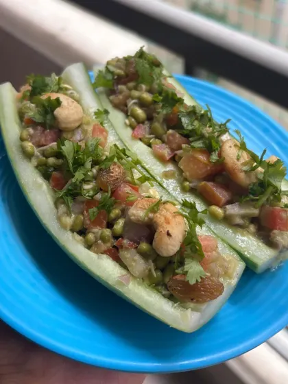 A creative and healthy appetizer of cucumber boats filled with a sprouted moong bean salad, cashews, and raisins.
