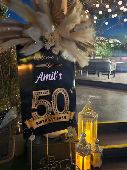 A personalized welcome sign for Amit's 50th birthday bash. The design features a bold, diamond-studded '50' and is surrounded by elegant lanterns for a warm, inviting entrance.