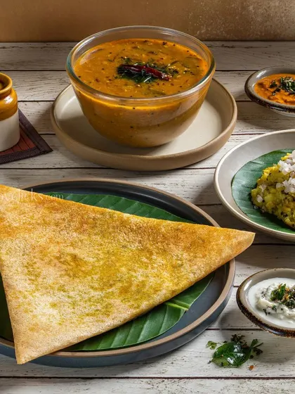 A simple and elegant presentation of a plain dosa with sambar and chutneys, perfect for a menu photograph.