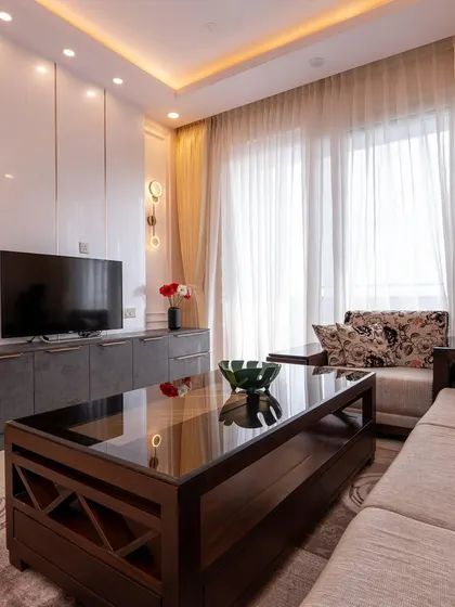 The living room features a comfortable sofa and a sleek, dark-toned TV console that provides ample storage, keeping the area tidy.