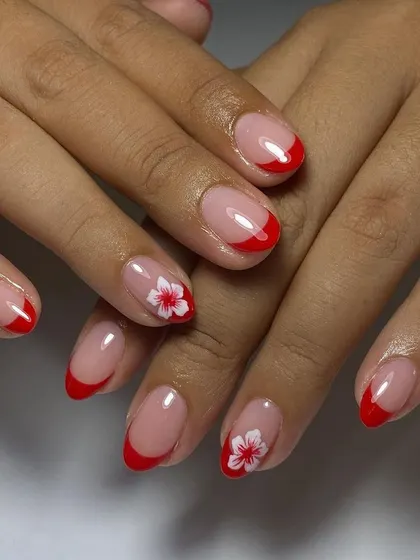 A classic red French manicure with a delicate, hand-painted white flower accent.