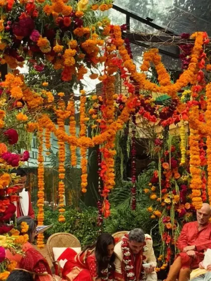 An intimate wedding ceremony with the couple surrounded by family under a canopy of marigolds.