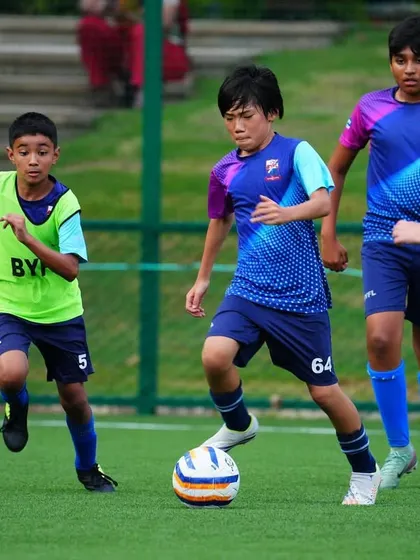 A player dribbles with speed and control during a U13 training drill.