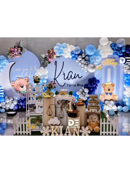 A beautiful teddy bear theme for Kian's first birthday. The 'Love you to the moon & back' backdrop is framed by a stunning blue and silver balloon arch, creating a dreamy and loving atmosphere.