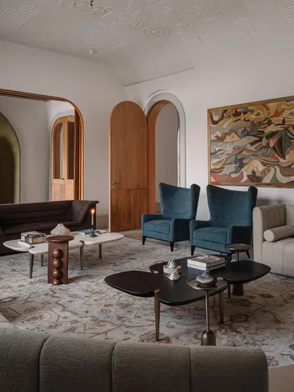 The formal living room is a curated collection of art and design, featuring furniture from DeMuro Das and Puru Das, intricate rugs, and mesmerizing marquetry veneer art, creating a space that is both luxurious and deeply personal.