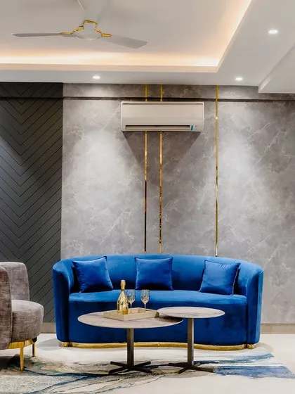 The seating area in the master suite features a royal blue sofa against a grey marble and wood-paneled wall with gold inlays. This is a perfect example of mixing materials for a rich, luxurious look.